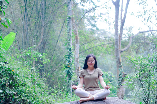 a woman sitting on top of a rock in a forest