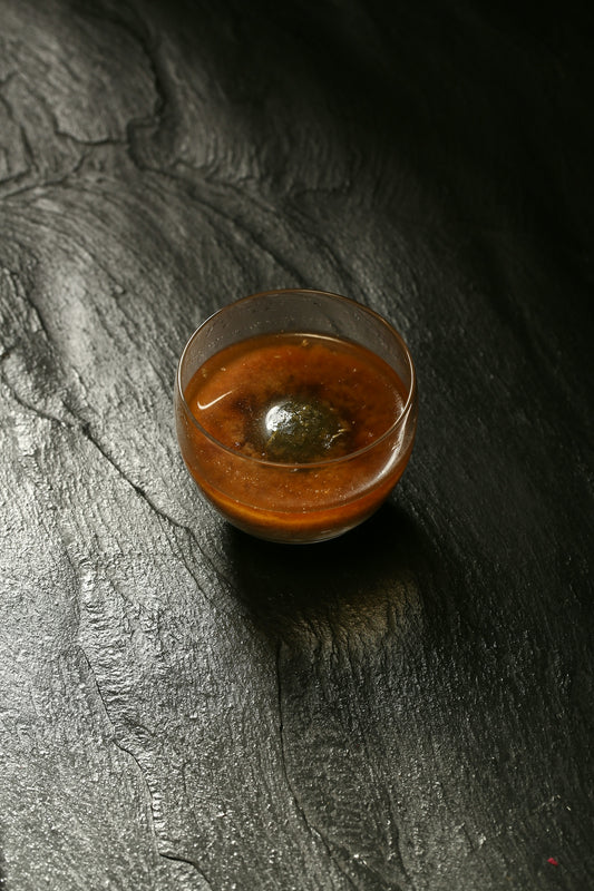 a small bowl of sauce on a black surface