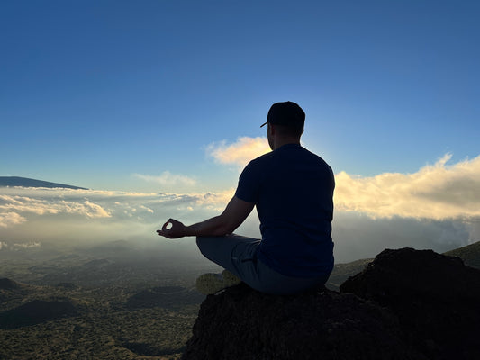 A man sitting on top of a mountain while meditating
