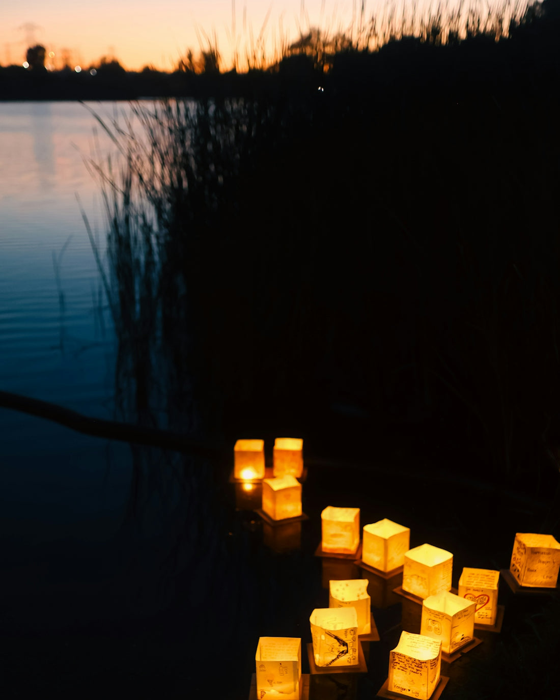 A number of lit candles near a body of water